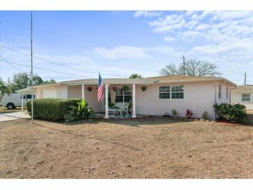 Pink single story home with covered porch and American flag at 2333 Tahitian Dr, Holiday, FL 34691