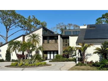 Contemporary two-story home featuring a circular driveway and tropical landscaping at 4402 Meadowwood Way, Tampa, FL 33618