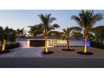 Charming home showcasing professional exterior lighting, meticulous landscaping, and a paved driveway at 4523 Clearwater Harbor S Dr, Largo, FL 33770