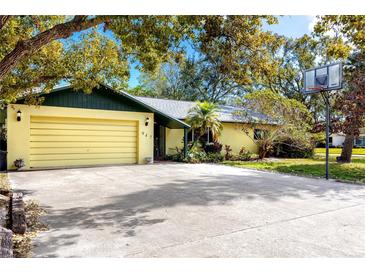 Yellow house with green roof, driveway, and basketball hoop at 947 Sousa Dr, Largo, FL 33771