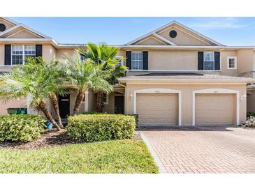 Inviting townhome with a brick driveway, two-car garage and tropical landscaping at 3900 Claybrook Dr, Wesley Chapel, FL 33544