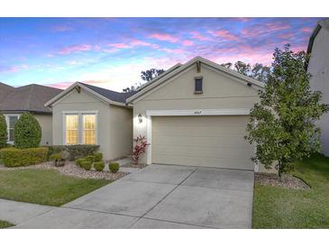 Charming single-story home with a two-car garage, landscaped yard, and beautiful dusk sky at 4927 Rolling Green Dr, Wesley Chapel, FL 33543