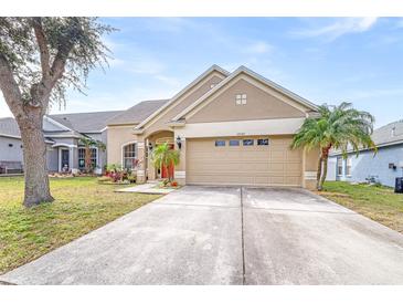 Tan one-story house with a two-car garage and landscaping at 12705 Bramfield Dr, Riverview, FL 33579