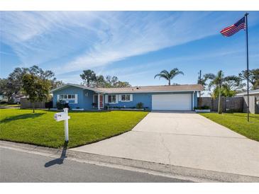 Charming single-story home with a well-manicured lawn, long driveway, and an American flag waving proudly at 1745 Emerald Dr, Clearwater, FL 33756