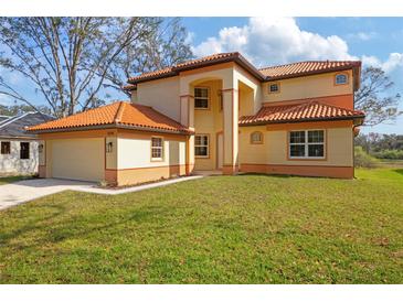 Two-story house with a tile roof, attached garage, and manicured lawn at 5226 Golf Links Blvd, Zephyrhills, FL 33541