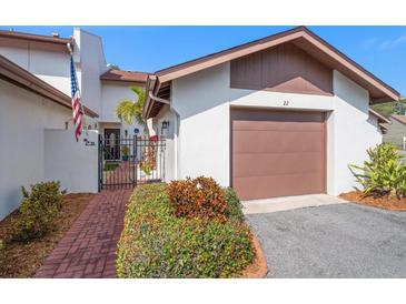 Charming townhome with brick walkway, gated entrance, and one-car garage, perfect for a cozy coastal lifestyle at 7501 Cumberland Rd # 22, Seminole, FL 33777