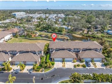 Stunning aerial view of townhomes featuring lush landscaping, a tranquil pond and attached garages at 868 Date Palm Ln, St Petersburg, FL 33707