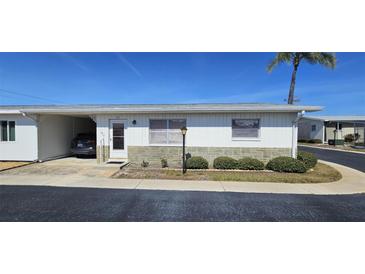 Charming home with a single-car carport, well-maintained landscaping, and a stone facade, set against a bright blue sky at 12400 Park Blvd # 417, Seminole, FL 33772