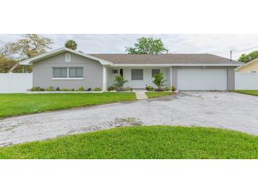 Gray house with white accents, a two-car garage, and well-manicured lawn at 1613 Druid E Rd, Clearwater, FL 33756