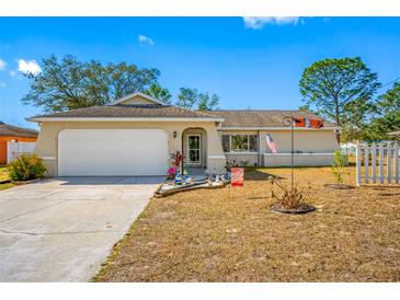 Charming single-story home with an attached garage, featuring a well-manicured lawn and decorative front yard at 10261 Horizon Dr, Spring Hill, FL 34608