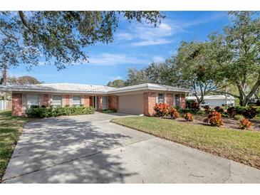 Brick ranch home with a large driveway and mature landscaping at 2054 Envoy Ct, Clearwater, FL 33764