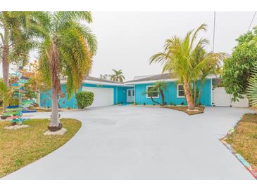 Charming waterfront home with a light blue exterior, palm trees, and a large driveway at 4643 Bay Crest Dr, Tampa, FL 33615