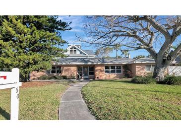 Charming single-story home featuring a well-maintained lawn, mature trees and inviting pathway to front door at 50 Acacia St, Clearwater Beach, FL 33767