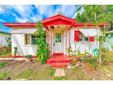 Charming single-story home with a red trimmed porch, white walls, and a garden of potted plants in the front yard at 5308 Ben Hur Dr, St Petersburg, FL 33708