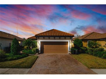 Charming home featuring a brick driveway, two-car garage, and a well-maintained front yard with lush landscaping at 11309 Callisia Dr, Odessa, FL 33556
