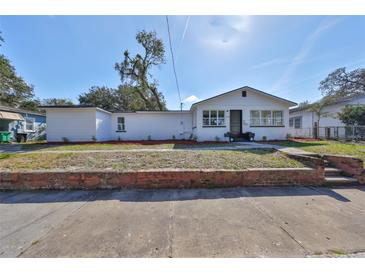 Charming single-story home showcasing a painted brick front and a well-maintained lawn at 1303 E New Orleans Ave, Tampa, FL 33603