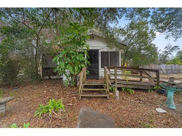 Charming cottage-style home with a screen porch and rustic wooden steps, nestled among lush trees at 3623 Whittier St, Tampa, FL 33619