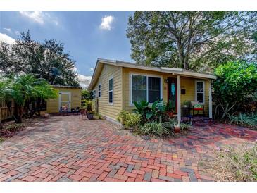 Charming yellow home featuring a brick driveway, covered porch, and well-maintained landscaping at 520 48Th N Ave, St Petersburg, FL 33703