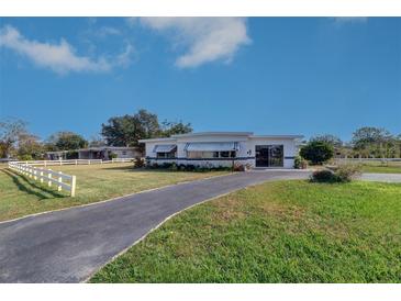 Ranch style home with a white exterior, landscaped lawn, and a long driveway at 1235 45Th N St, St Petersburg, FL 33713