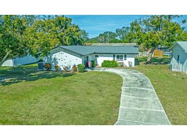 Charming single-story home featuring a long driveway and a well-manicured lawn with mature trees at 1436 Rose St, Clearwater, FL 33756