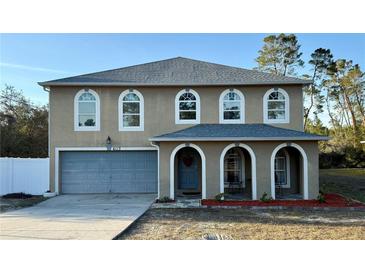 Charming two-story home featuring arched windows, a gray roof, and a spacious front porch at 6113 Freeport Dr, Spring Hill, FL 34606