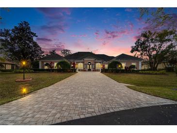 Stately home featuring a long brick driveway and lush landscaping, captured during a beautiful sunset at 8510 Kentucky Derby Dr, Odessa, FL 33556