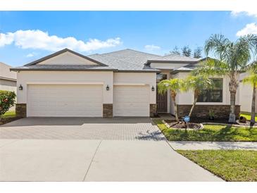 Well-maintained, single-story home with a three-car garage, desert landscaping, and decorative stone accents at 10063 Celtic Ash Dr, Ruskin, FL 33573