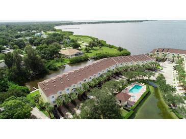 Scenic aerial view of waterfront townhomes with a pool and canal access, surrounded by lush greenery at 102 Brent Cir, Oldsmar, FL 34677