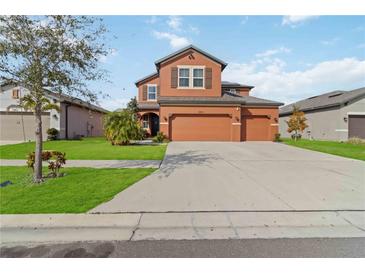 Inviting two-story home features a three-car garage, arched entryway, and well-manicured lawn at 11804 Bluegrass Field Ct, Riverview, FL 33579