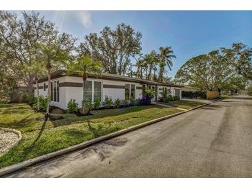 Charming exterior featuring well-maintained landscaping, mature trees, and a neatly paved driveway at 525 Lamara Ne Way, St Petersburg, FL 33704