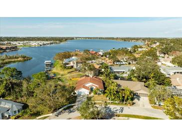 Aerial view of a beautiful waterfront home surrounded by lush landscaping and a serene lake at 10562 99Th St, Largo, FL 33773