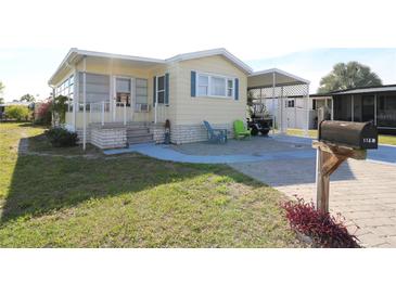 Charming home featuring light yellow siding, blue shutters, and a brick foundation with an inviting front yard at 114 W Saint Johns Way, Apollo Beach, FL 33572