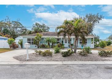 Charming single-story home with a well-maintained front yard featuring palm trees and a quaint front porch at 1211 Carolyn Ln, Clearwater, FL 33755