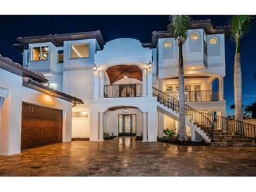 Elegant two-story home featuring a beautiful facade, ornate ironwork, and a warm, inviting entrance at nighttime at 15912 Gulf Blvd, Redington Beach, FL 33708