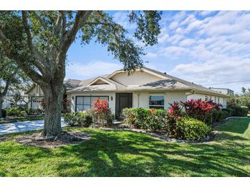 Single-story home with a screened porch, mature landscaping, and a large tree at 2517 Lynx Rd # 20, Sun City Center, FL 33573