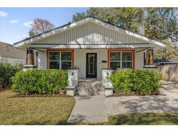 Charming home featuring a well-manicured lawn, complemented by a white facade and beautiful landscaping at 321 W Wilder Ave, Tampa, FL 33603