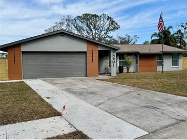 Charming single-story home with a gray and brown exterior, featuring a two-car garage and a well-manicured lawn at 7281 Channelside N Ln, Pinellas Park, FL 33781