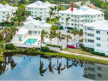 An aerial view of the Condo community, featuring a pool, lush landscaping, and water views at 7611 34Th W Ave # 303, Bradenton, FL 34209