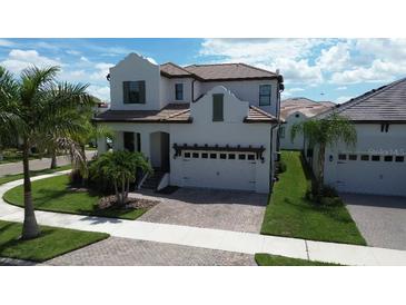 Charming stucco home with a tile roof, a paved driveway, and a well-maintained lawn at 923 Seagrape Dr, Ruskin, FL 33570