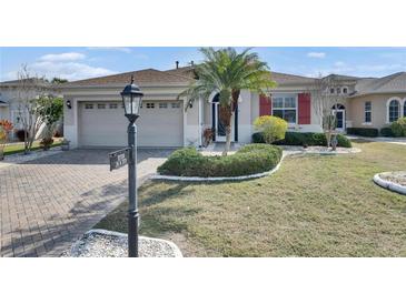 Well-maintained home with a brick driveway, lush lawn, and attractive landscaping at 1004 Regal Manor Way, Sun City Center, FL 33573