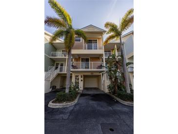 Charming townhouse with a two-car garage and multiple balconies surrounded by lush tropical landscaping and mature palm trees at 3244 Mangrove Point Dr, Ruskin, FL 33570