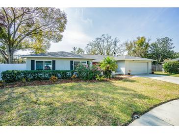 Charming single-story home featuring a lush front lawn, flowering bushes, and a two-car garage at 3704 Thornwood Pl, Tampa, FL 33618