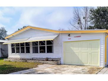 Charming home exterior featuring a one-car garage and a covered sunroom with ample windows at 4425 Autumn Palm Dr, Zephyrhills, FL 33542