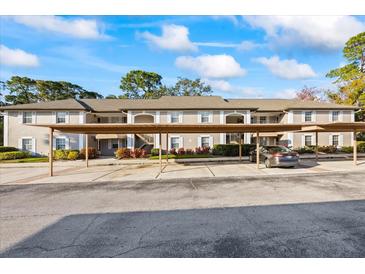 Condo building exterior showing the carports, second story, neutral paint, and manicured landscaping at 5265 E Bay Dr # 424, Clearwater, FL 33764