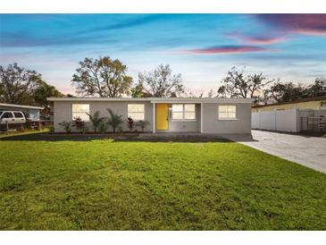 Charming single-story home with a well-manicured lawn and bright yellow front door at 8303 Croton Ave, Tampa, FL 33619