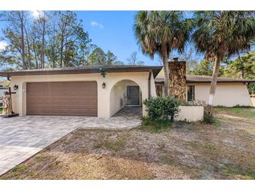 Charming single-story home featuring a brick driveway, attached garage, and stone chimney at 9445 Preston Rd, Brooksville, FL 34601