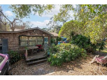 Rustic wood-sided home with a covered porch and mature landscaping at 9810 Parsons St, Tampa, FL 33615