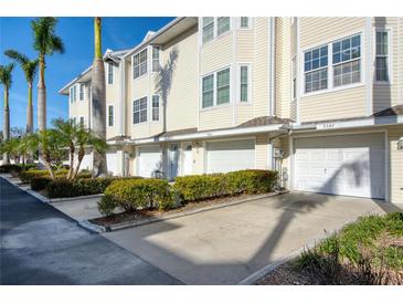 Inviting townhouse with a garage and driveway, complemented by lush landscaping and beautiful palm trees at 9347 Blind Pass Rd, St Pete Beach, FL 33706