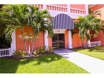 Building entrance featuring manicured landscaping, a black and white awning, and fresh green lawn at 1900 68Th N St # 104, St Petersburg, FL 33710