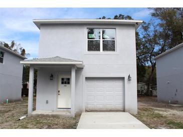 Two-story home featuring a garage, white door, and a modern, gray stucco exterior at 2222 E Emma Street, Tampa, FL 33610